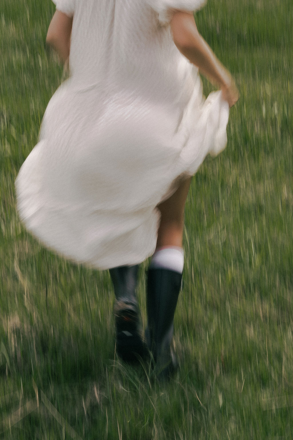 Running freely in a sunlit meadow, a young girl dances with joy, her white dress billowing in the breeze during a warm summer afternoon